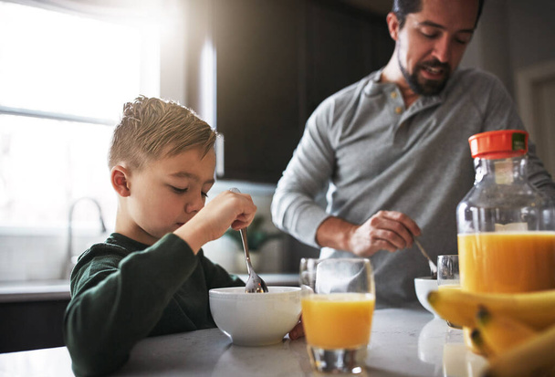 Kahvaltı günün en önemli öğünüdür. Genç bir çocuk ve babası mutfakta kahvaltı yapıyor. - Fotoğraf, Görsel