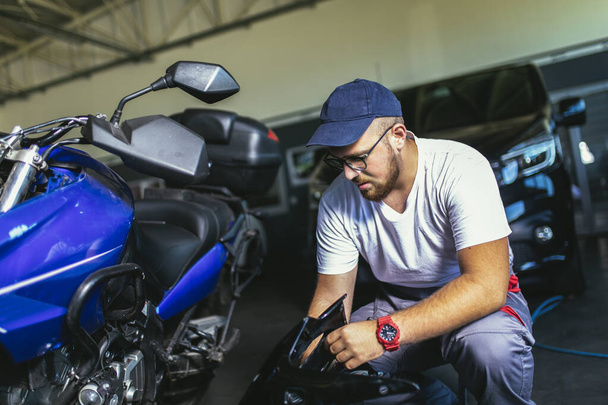 Professional motorcycle mechanic working in bike repair service - Zdjęcie, obraz