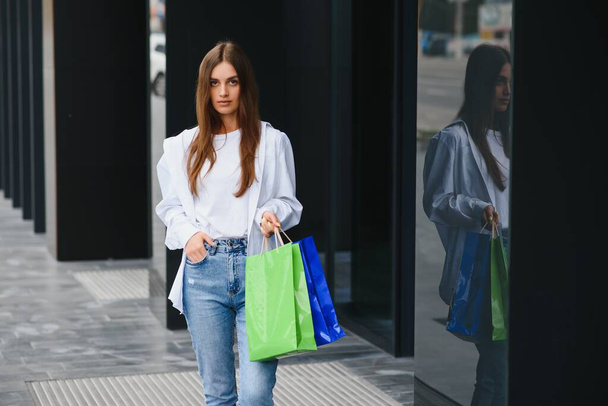woman holding shopping bags of luxury brands, walking near shopping mall. - Fotografie, Obrázek