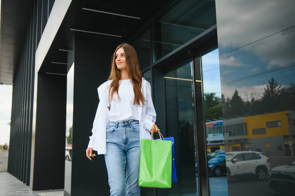 Modna piękna szczęśliwa kobieta stojąca z torbami na zakupy w pobliżu centrum handlowego w Czarny Piątek - Zdjęcie, obraz