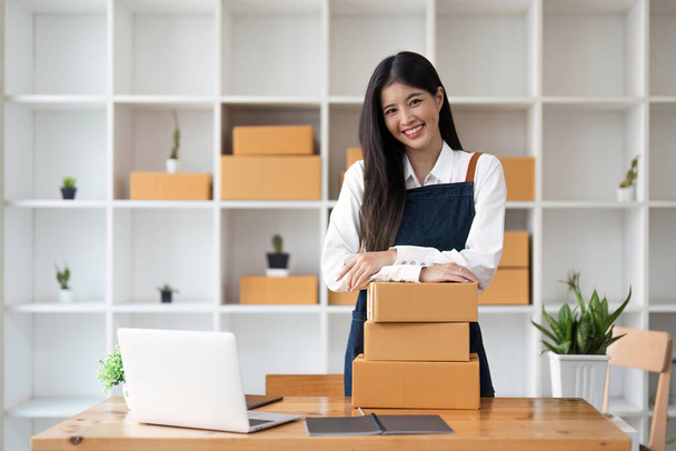 Young pretty asian start up business woman in apron working with online parcel box warehouse selling online product. - Фото, зображення