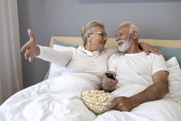Старша пара розслабляється в спальні і дивиться телевізор
. - Фото, зображення