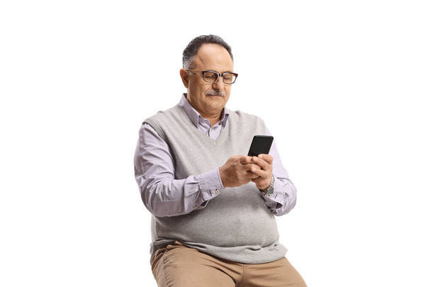 Mature man sitting and typing on a mobile phone isolated on white background - Фото, изображение