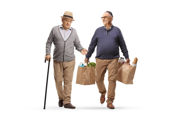 Mature man walking, carrying grocery bags and having a conversation with a pensioner isolated on white background - Φωτογραφία, εικόνα