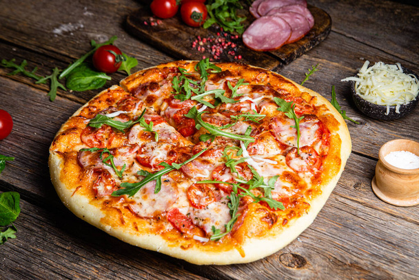 Аппетитная пицца с ветчиной на деревянном фоне - Фото, изображение