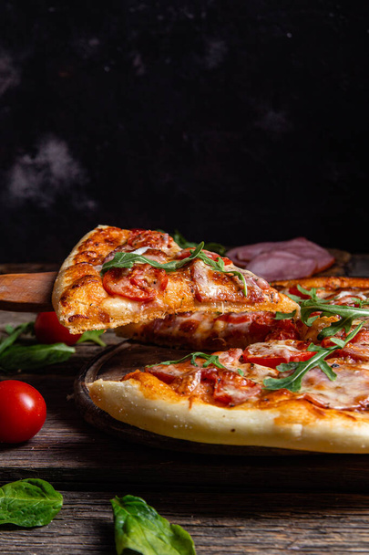 Appetizing pizza with ham on a wooden background - Photo, Image