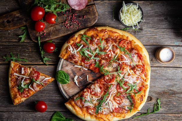 Appetizing pizza with ham on a wooden background - Fotó, kép