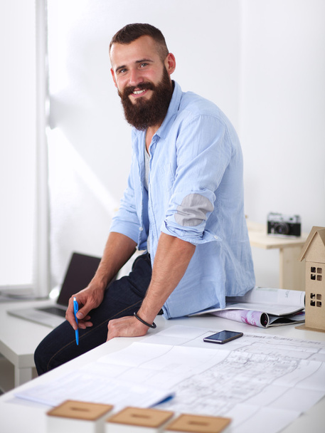 Portrait of male designer in hat with blueprints at desk - Foto, imagen