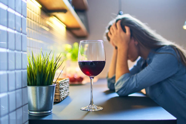 Lonely depressed drinking woman suffering from alcohol addiction abuse with red wine glass alone at home.              - Foto, imagen