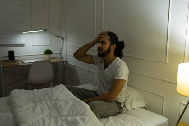 Jeune homme malade souffrant d'un mal de tête en étant éveillé la nuit après s'être réveillé au lit en pensant à ses problèmes - Photo, image