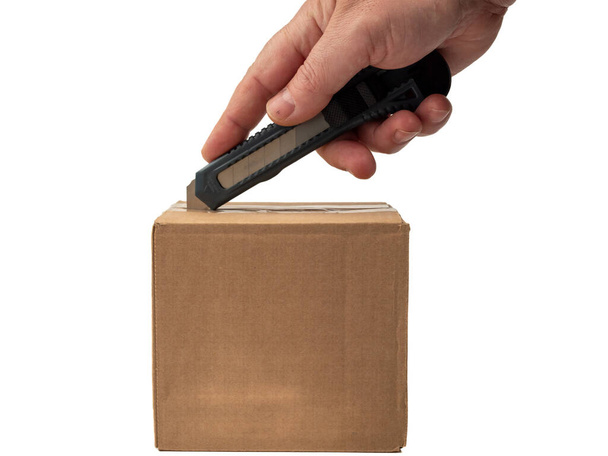 La caja de cartón se abre con un cuchillo. Fondo blanco. - Foto, Imagen