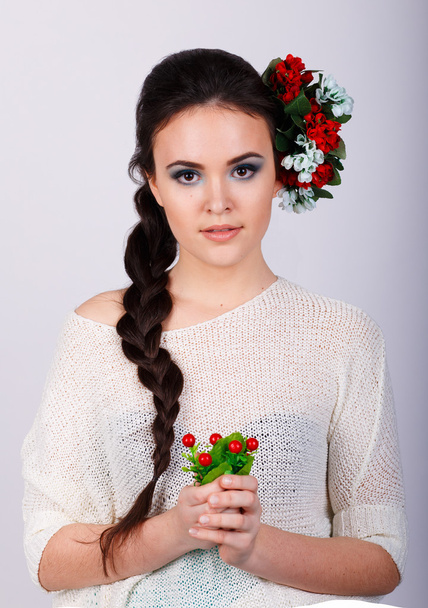 Girl with long dark plait and flowers in her hair.Studio portrait of a beautiful brunette girl - Photo, Image