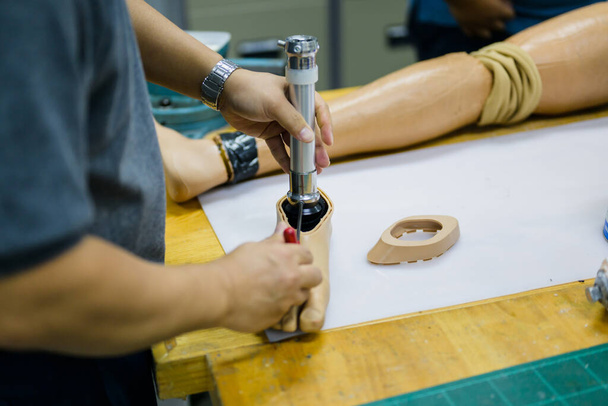 Mężczyzna pracownik montujący części sztucznej nogi w warsztacie produkcji protez, Inżynier ds. rozwoju z zaawansowaną technologią w produkcji protez, Nowa produkcja sztucznych kończyn dla - Zdjęcie, obraz