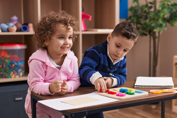 Entzückende Jungen und Mädchen spielen mit Mathe-Puzzlespiel am Tisch im Kindergarten - Foto, Bild