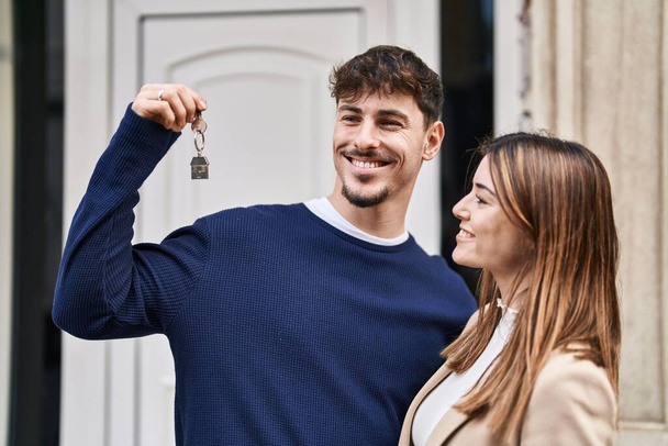Чоловік і жінка пара обіймають один одного тримаючи ключ нового будинку на вулиці
 - Фото, зображення