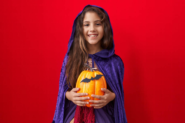 Piccola ragazza ispanica indossando strega costume di Halloween guardando positivo e felice in piedi e sorridente con un sorriso fiducioso mostrando i denti  - Foto, immagini