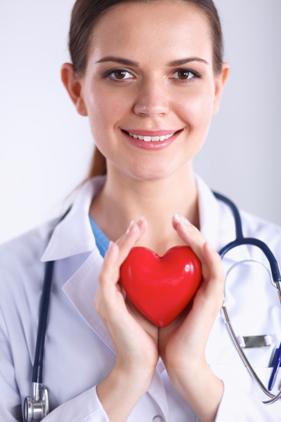 Young woman doctor holding a red heart, isolated on white background - Фото, изображение