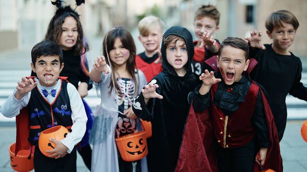 Группа детей в костюме на Хэллоуин делает пугающий жест на улице - Фото, изображение
