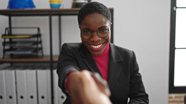 Mujer afroamericana trabajadora de negocios sonriendo confiada apretón de manos en la oficina - Foto, Imagen