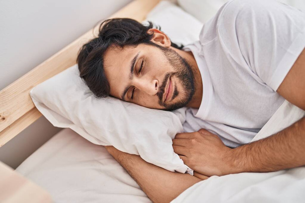 Молодой латиноамериканец лежит на кровати и спит в спальне. - Фото, изображение