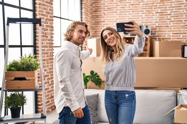 Man and woman couple make selfie by the smartphone sitting on sofa at new home - Foto, Bild