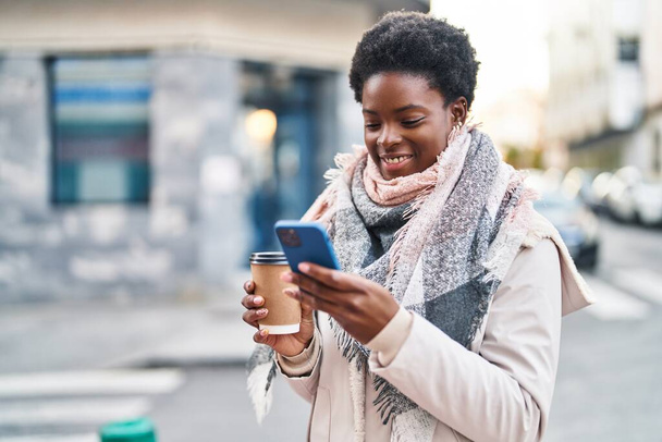 Mujer afroamericana usando smartphone bebiendo café en la calle - Foto, imagen