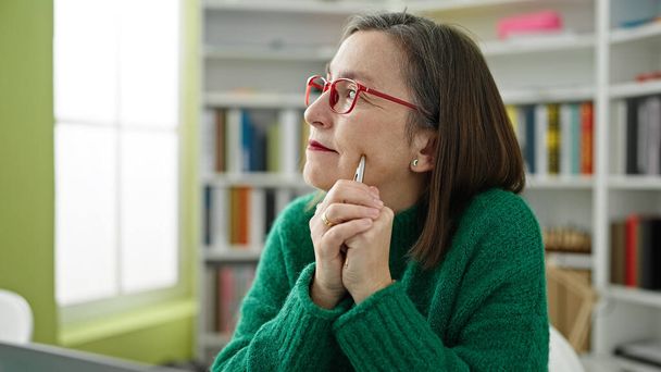 Starší hispánská žena s šedými vlasy myšlení v knihovně - Fotografie, Obrázek
