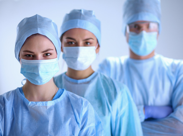 Equipe de cirurgiões, usando uniformes protetores, bonés e máscaras - Foto, Imagem