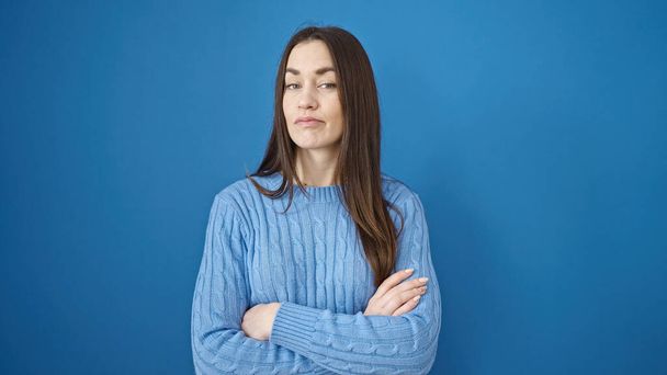 Young caucasian woman standing with serious expression and arms crossed gesture over isolated blue background - Photo, Image