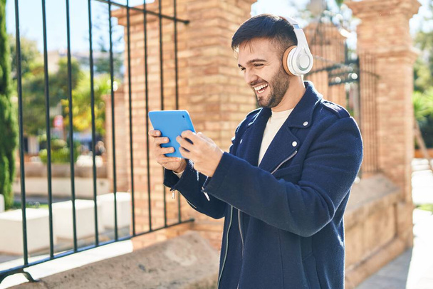 Молодий іспаномовний чоловік посміхається впевнено граючи відеоігри на вулиці
 - Фото, зображення