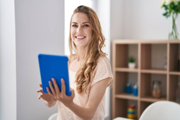 Young blonde woman smiling confident using touchpad at home - Fotó, kép