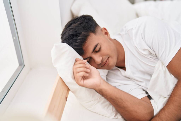 Jeune homme hispanique couché sur le lit dormant dans la chambre - Photo, image