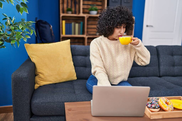 Young middle east woman using laptop having breakfast at home - Foto, imagen