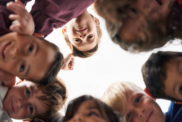 Gruppo di studenti bambini sorridenti fiduciosi in piedi con la testa insieme in classe - Foto, immagini
