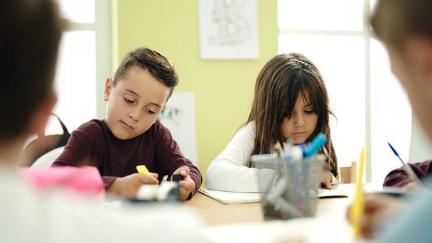 Gyerekek egy csoportja ül az asztalon és tanul az osztályteremben. - Fotó, kép
