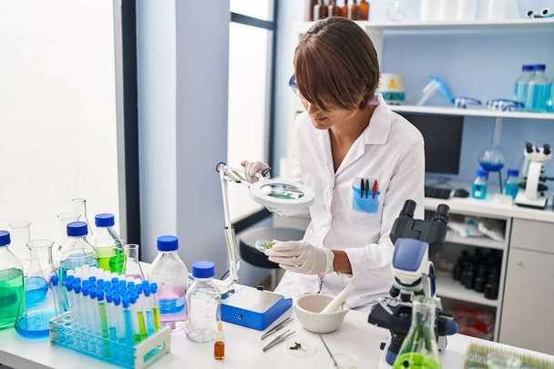Νεαρή όμορφη Ισπανίδα επιστήμονας χρησιμοποιώντας λούπα στο εργαστήριο - Φωτογραφία, εικόνα