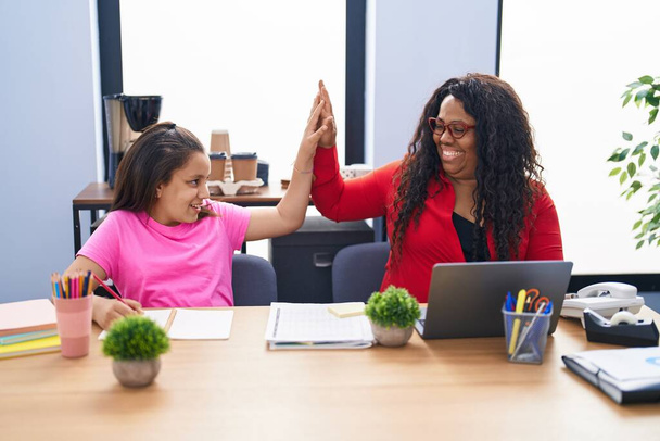 Mother and daughter smiling confident high five with hands raised up at office - Foto, Imagem