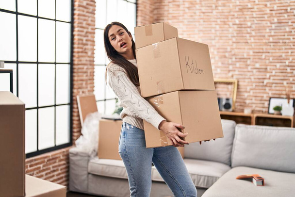 Young woman holding packages at new home - Foto, Imagen