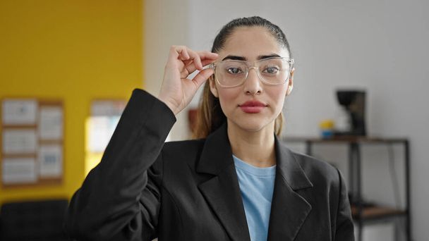 Young beautiful hispanic woman business worker standing with serious expression at office - Foto, Bild