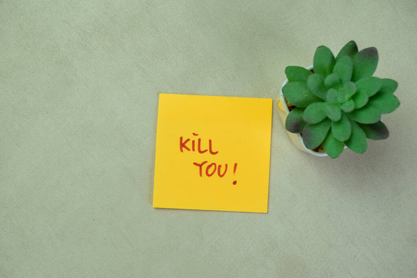 Concept of Kill You! write on sticky notes isolated on Wooden Table. - Photo, image