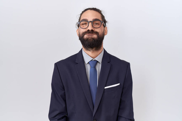 Hispanic man with beard wearing suit and tie puffing cheeks with funny face. mouth inflated with air, crazy expression.  - Foto, imagen