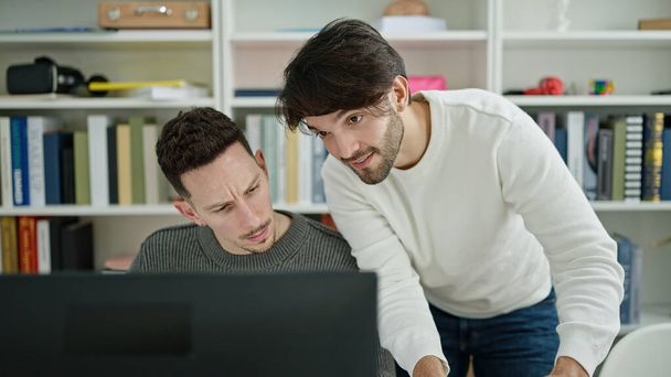 Dois estudantes homens usando computador estudando na universidade da biblioteca - Fotografia, imagem