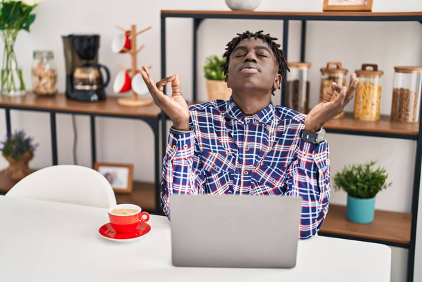African american man doing yoga exercise sitting on table at home - Photo, Image