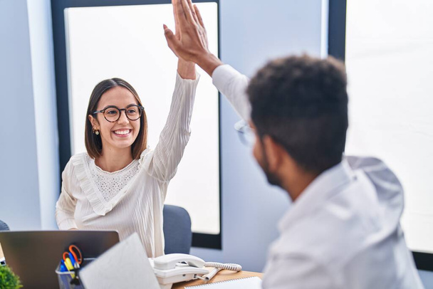 Мужчина и женщина деловые работники "дай пять" с поднятыми руками в офисе - Фото, изображение