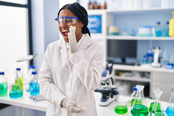 Femme afro-américaine travaillant au laboratoire scientifique désemparée et confuse à bras ouverts, aucune idée et visage douteux.  - Photo, image