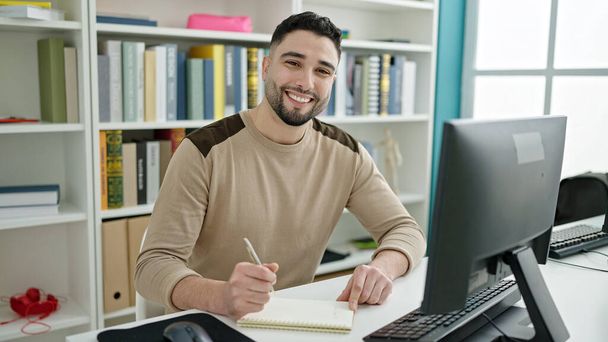 Estudiante árabe joven utilizando la escritura por computadora en el cuaderno en el aula universitaria - Foto, imagen