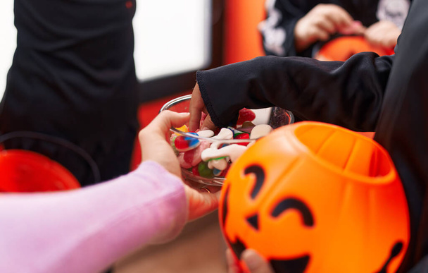 Grupo de crianças vestindo trajes de Halloween recebendo doces em casa - Foto, Imagem