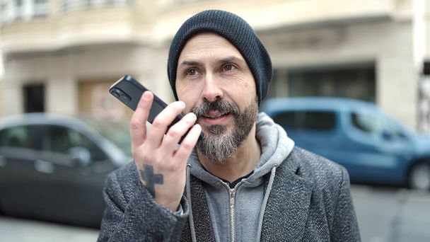 Молодий лисий чоловік надсилає голосове повідомлення зі смартфоном на вулиці
 - Фото, зображення