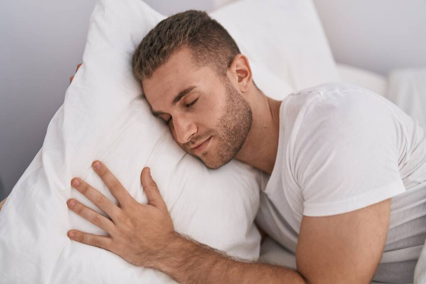 Fiatal fehér férfi fekszik az ágyon alszik a hálószobában - Fotó, kép