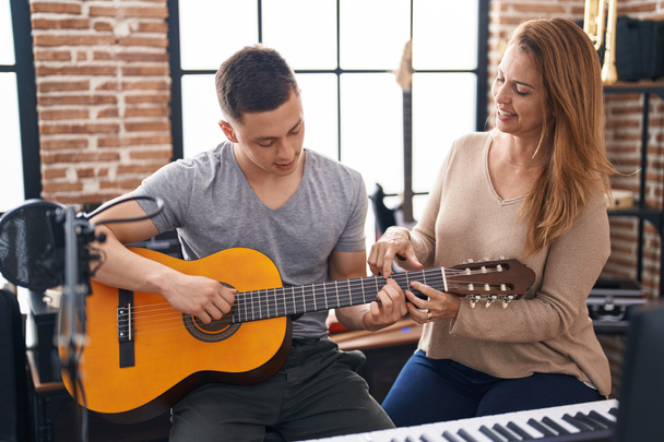 Man and woman musicians having classic guitar lesson at music studio - Foto, Bild